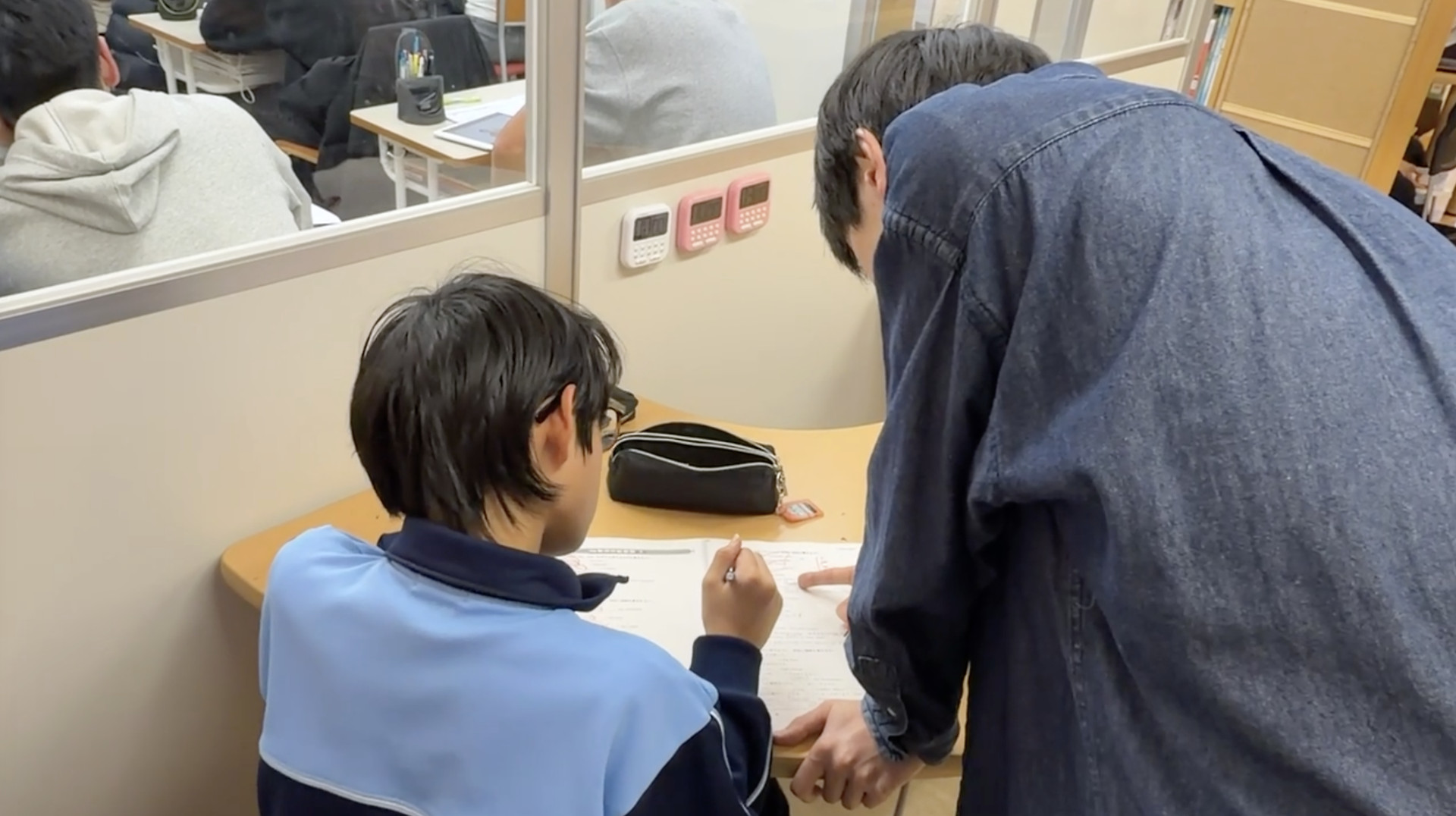 先生と生徒が、教材の同じ箇所を見ながら確認しています。