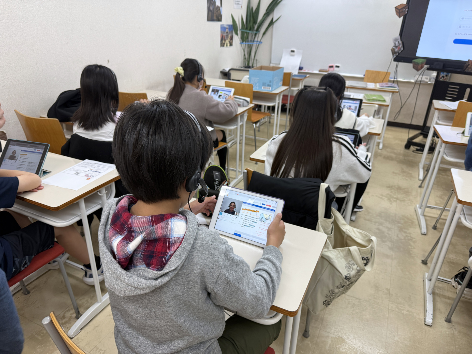 ヘッドセットを使い、画面を見ながら学習する小学生たち。