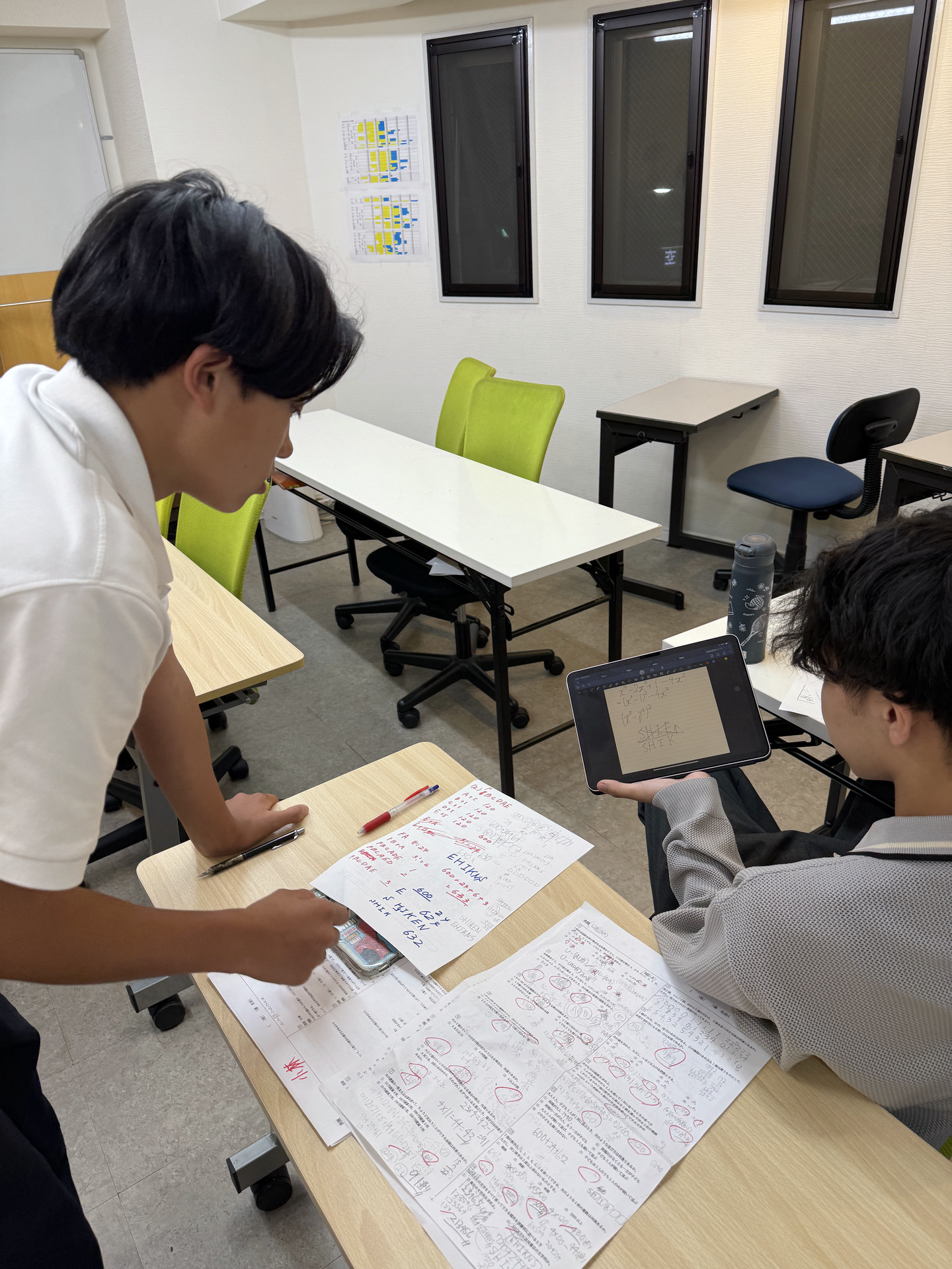 先生と生徒が教材とタブレットを一緒に確認する様子